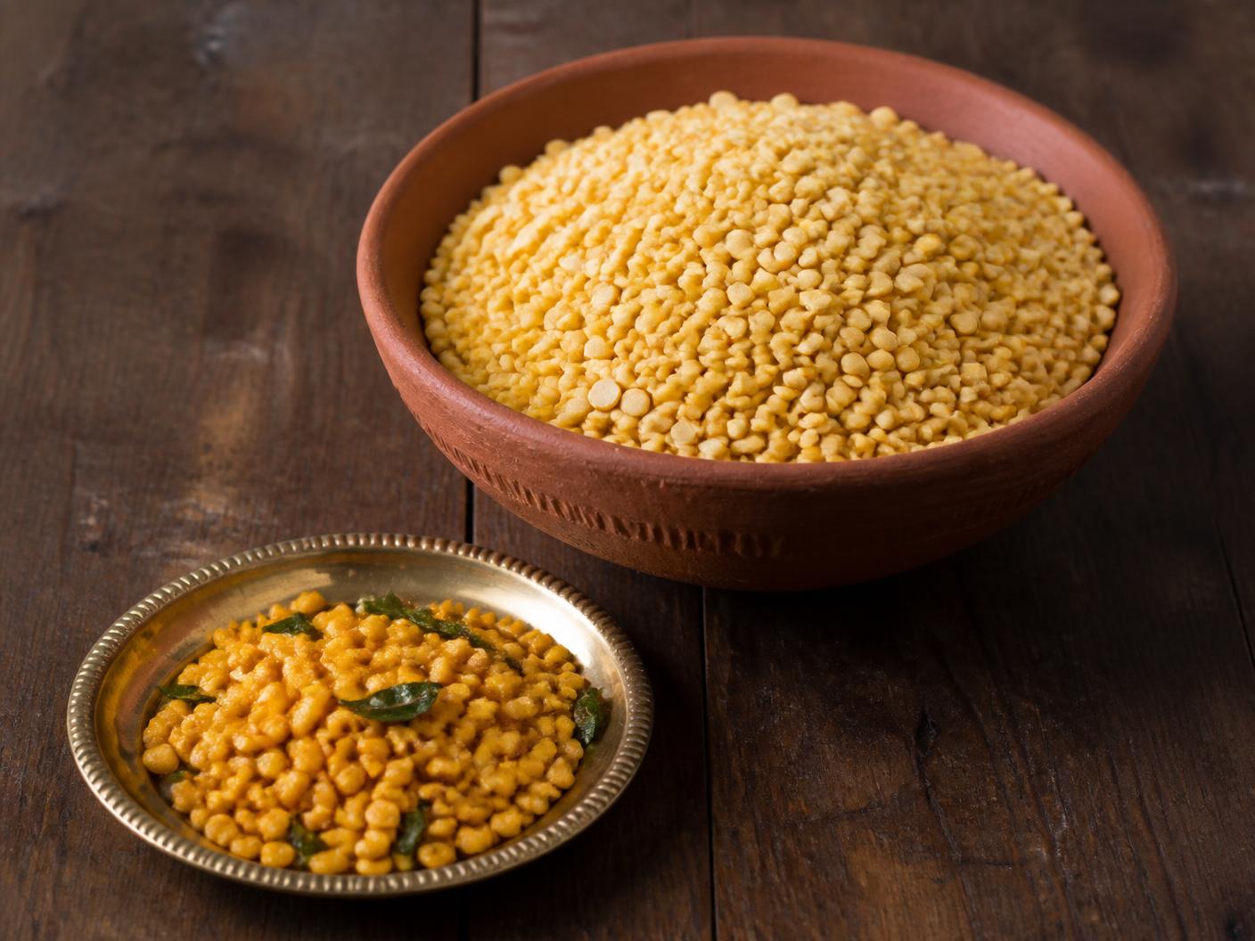 Whole green moong beans in a jute sack beside a bowl of yellow split moong dal